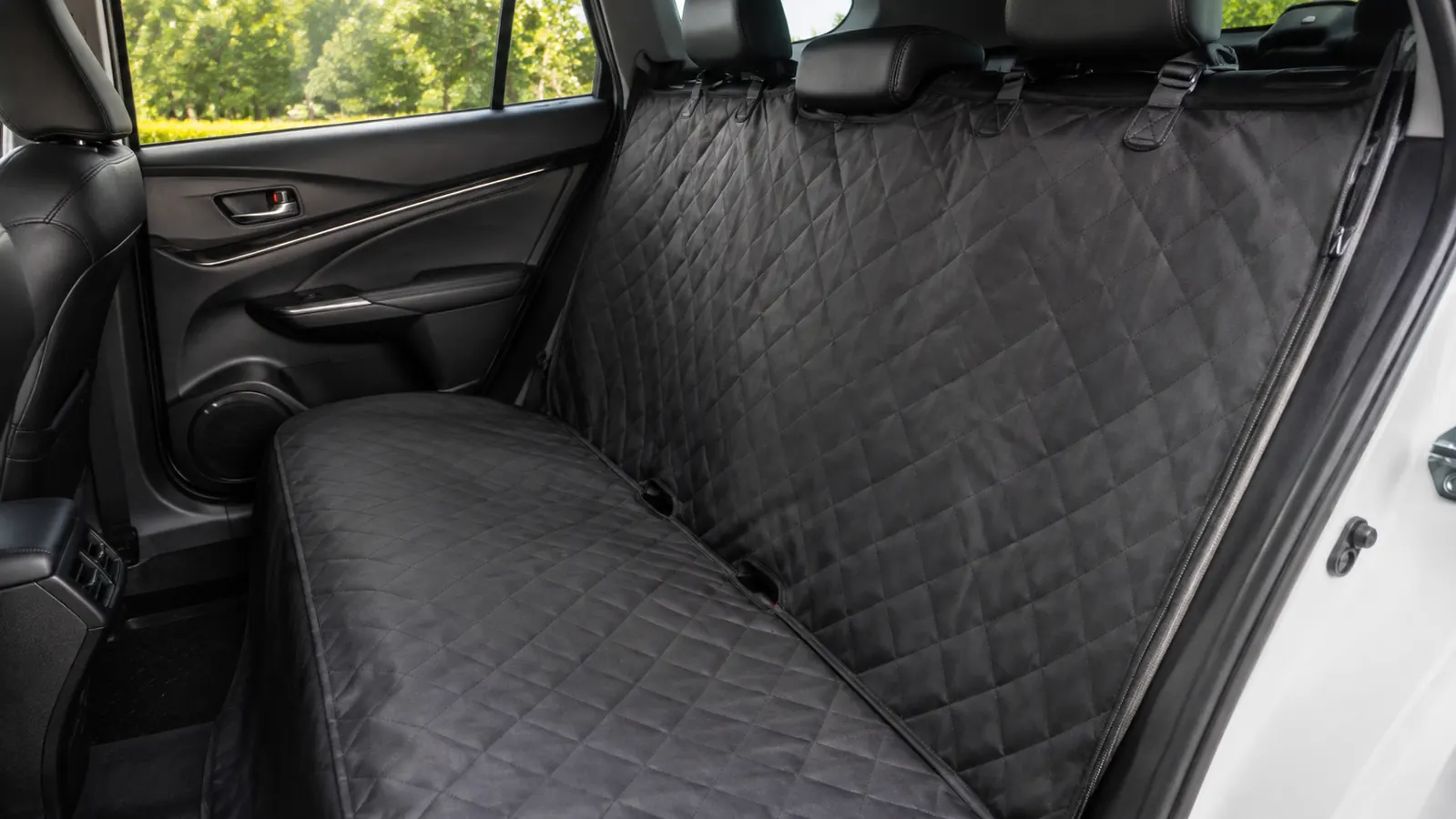A clean back seat of a car with a seat cover still in place after the dog has been removed, no loose fur or dirt visible